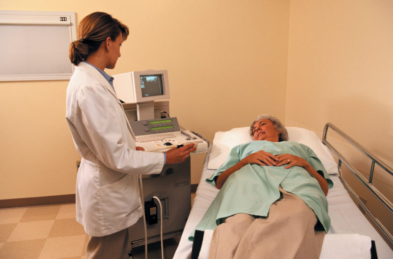 female doctor talking to female patient lying on gurney